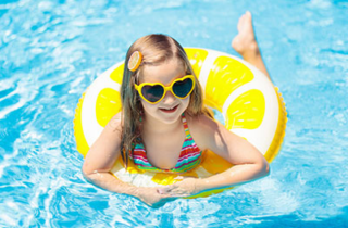 A girl uses a yellow pool tube in a pool.
