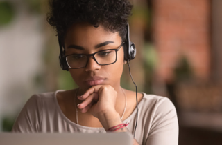 A black teenage girl wears headphones and looks at a screen.