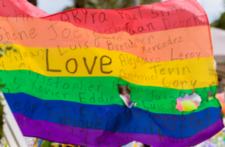 An LGBTQ+ Pride Flag says "Love" and features the names of the Pulse Nightclub Shooting.
