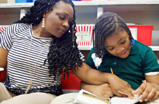 A teacher and student reading a book.
