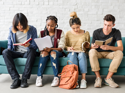 A diverse group of teens sit together reading books.