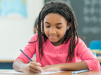 A female student smiling and writing